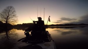 silhouette of kayak fisher on lake